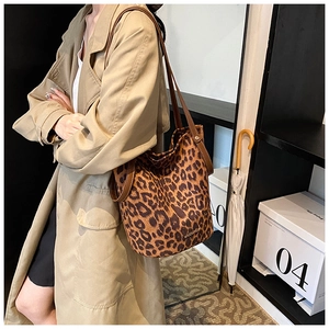Detailed side view of leopard print bucket bag with brown leather straps and metal logo