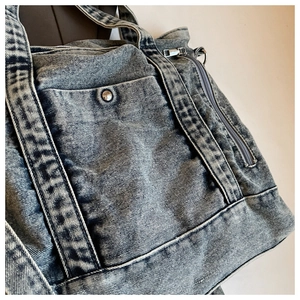 Detailed shot of heavy washed denim tote bag featuring metal zipper and reinforced stitching