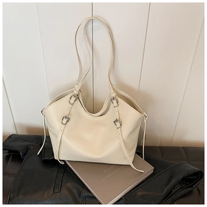 Close-up of cream tote bag with silver metal buckles and smooth leather texture