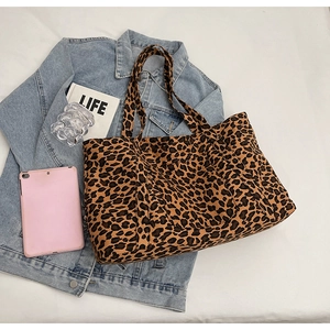 Flat lay of large leopard print tote bag with denim jacket and daily essentials