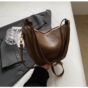 Close-up of retro brown crescent hobo bag with vintage gold zippers and dual straps