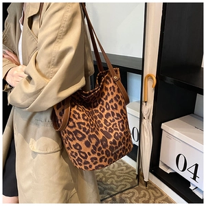Detail view of large leopard print bucket bag with brown leather strap on model