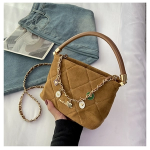 Detailed close-up of brown quilted handbag with golden chain and colorful heart charms