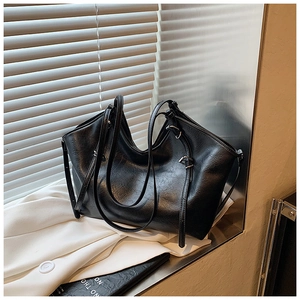 Detail of large black tote bag with wrinkled PU leather texture and silver buckle