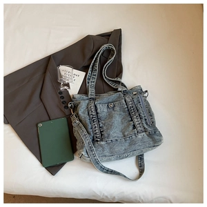 Detail of vintage washed blue denim tote bag with metal snap pocket and adjustable strap