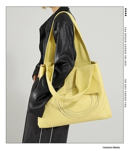 Detail of soft yellow leather tote with circular patterns and textured litchi grain