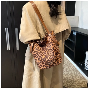 Close-up of leopard print bucket bag with long shoulder strap and brand detail on suede