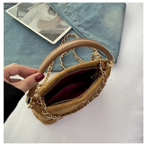 Detail view of brown suede chain handbag with cylindrical handle and gold metal zipper