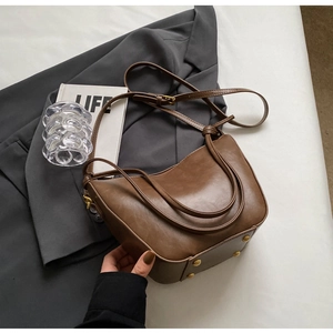 Close-up of brown matte faux leather bucket bag with gold rivets and adjustable strap