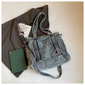 Close-up of vintage wash denim tote bag showing functional pockets and metal snap button
