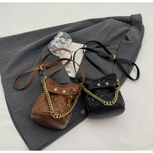 Close-up of quilted bucket bags in black and brown with golden chain straps