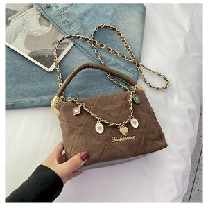 Close-up of brown quilted suede bag with gold chain strap and heart charm accents