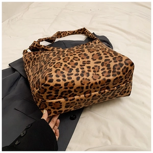 Detail showing the leopard print tote bag's pebbled leather texture and wide strap