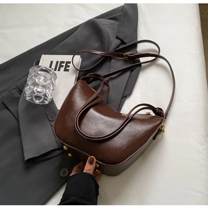 Detail of vintage brown crescent bucket bag showing glossy texture and brass metal base