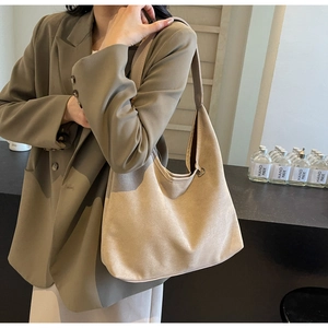 Détail du grand sac cabas en suédine beige avec bandoulière sur une veste de blazer