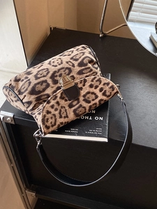 Chic leopard print crossbody bag with gold hardware and black leather trim on a desk