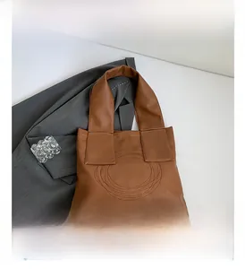 Detail view of brown tote bag with unique circular stitching on textured PU leather