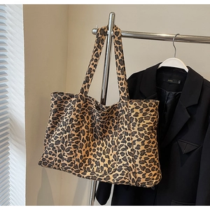 Close-up of leopard print canvas tote bag with front pocket hanging on a metal rack