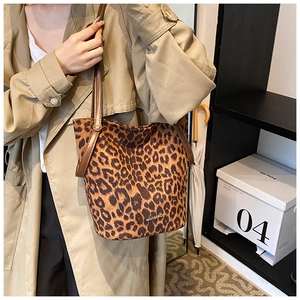 Detailed close-up of leopard print bucket bag featuring brown leather strap and logo