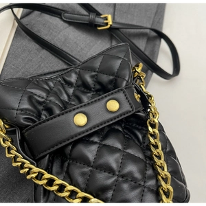 Detailed macro view of black quilted leather texture with gold chain strap and metal rivets
