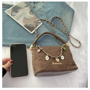 Detailed view of brown quilted suede handbag with gold heart charms and chain strap