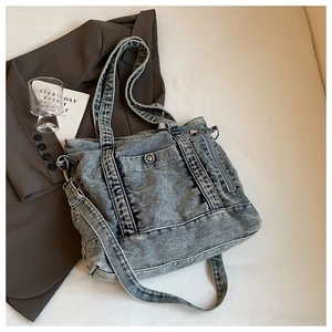 Detailed view of washed denim tote bag with metal zippers, D-rings and adjustable strap