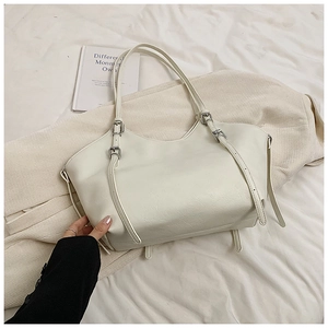 Close-up of white tote bag with lychee texture leather and silver buckle strap detail