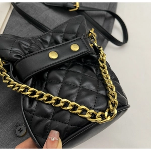 Macro shot of black quilted bucket bag featuring gold chain handle and rivet hardware details