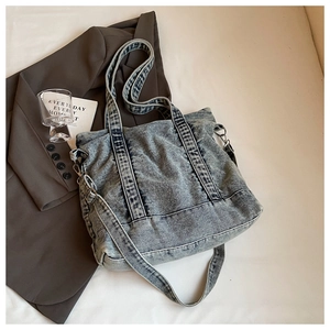 Detail view of washed denim tote bag with metal buckles and sturdy shoulder strap