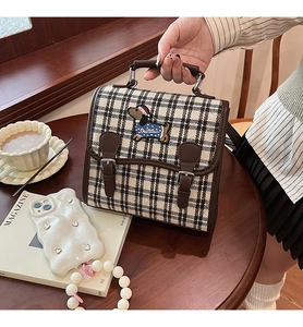 Detailed view of checkered backpack with embroidered dachshund and leather strap