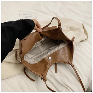 Interior detail of brown tote bag showing light grey lining and zip pocket with magnetic snap