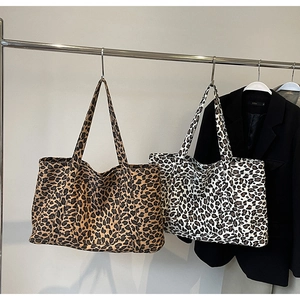 Detailed view of large leopard print canvas tote bags in brown and white on a metal hanger