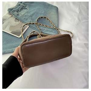 Detailed bottom view of brown suede handbag featuring a gold chain strap and smooth base