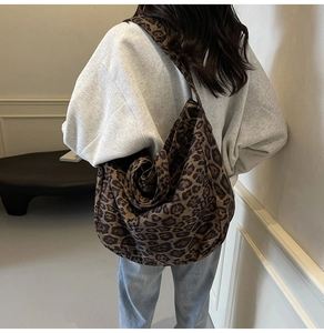 Detailed back view of a large leopard print canvas tote bag carried by a model