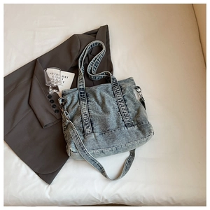Detail of vintage blue denim tote bag with adjustable strap and carry handle