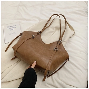 Detail of vintage brown tote bag showing soft faux leather texture and decorative buckles