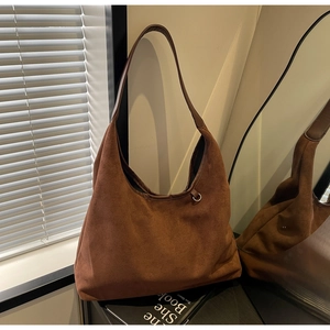 Détail du sac hobo en daim marron avec large bandoulière et anneau métallique décoratif