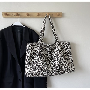 Detailed view of the large leopard print tote bag hanging on a minimalist wall hook