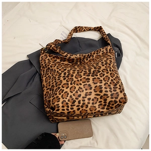 Close-up of leopard print canvas bag featuring golden metal rings and wide shoulder strap