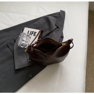 Top view of deep brown matte leather crescent bag with gold zipper and interior lining