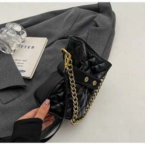 Detail of black quilted leather bucket bag with gold chain and metal hardware accents