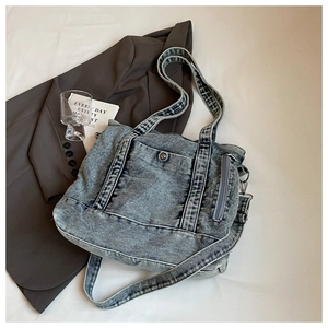 Detail view of denim tote bag with contrast stitching and pocket on casual blazer