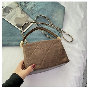 Detailed close-up of brown quilted handbag with metal chain strap and suede texture