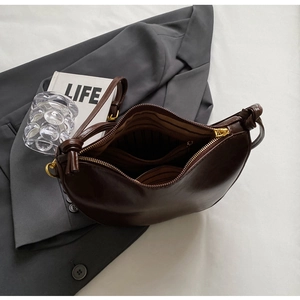 Detail of dark brown leather crescent bag showing striped lining and inner compartments