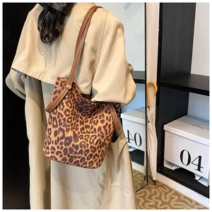 Detail of leopard print bucket bag with brown leather strap and golden rivet accents