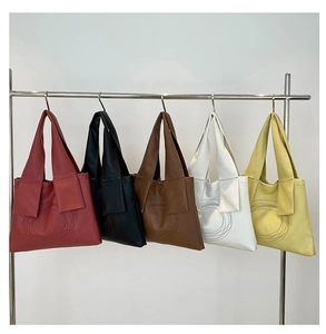 Minimalist leather tote bags in five colors hanging on a modern stainless steel rack