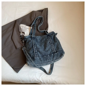 Detail of washed denim tote bag with adjustable shoulder strap on a white background