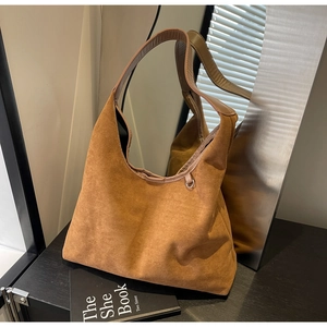 Gros plan détaillé sur la texture en daim souple et la large bandoulière du sac marron