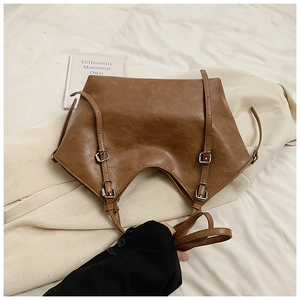 Detail view of caramel brown faux leather tote with vintage silver buckles and soft texture