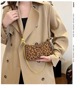 Leopard print baguette bag with gold chain and wide strap on khaki trench coat model
